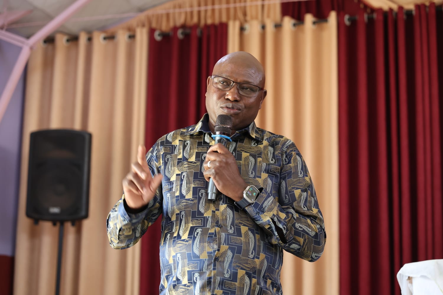 Patrick Kiptoo speaking into a microphone and gesturing with his hand.